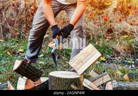 Man with strong hands chopping wood with an ax pieces fly apart. Stock Photo