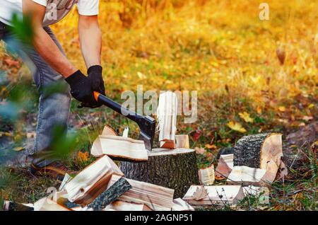 Man with strong hands chopping wood with an ax pieces fly apart. Stock Photo