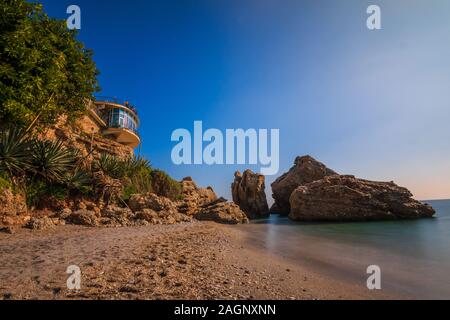 Sandy beach on the Spanish coast of the Costa del Sol. Viewpoint Balcon Europa in Nerja on sunny day as a view over the Mediterranean. View of rocks w Stock Photo
