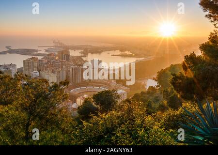 Evening sun on the horizon over Spanish city of Malaga. Costa del Sol at sunset with a panoramic view of the harbor, the houses, the trees, bullring Stock Photo