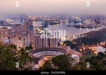 Malaga in the evening mood on the Spanish Mediterranean coast. City view on the Costa del Sol with trees, street lamps, ferris wheel, ships Stock Photo