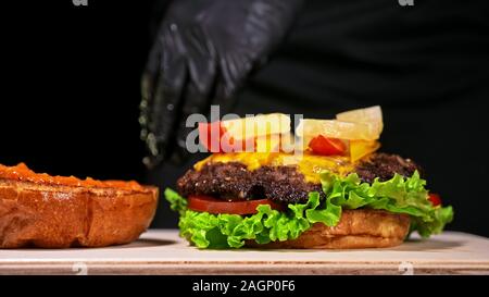 Craft burger is cooking. Consist: red sauce salsa, lettuce, red onion, pickle, cheese, chilli green pepper, air bun and marbled meat beef. Stock Photo