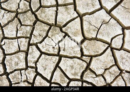 Pattern of cracked ground at the seashore. Brown, beige, light tan and grey colored background. Stock Photo