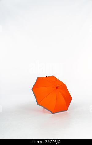 An opened orange umbrella with gray edges in a photo studio on a white background. Isolated on White background, space for text. Stock Photo