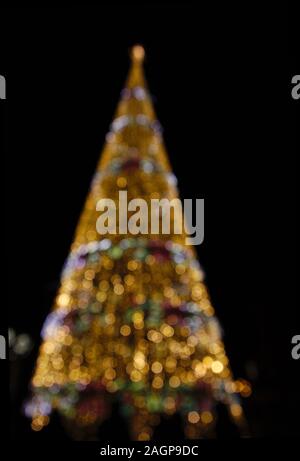 Defocused Christmas tree lights contrast with the darkness of the night Stock Photo