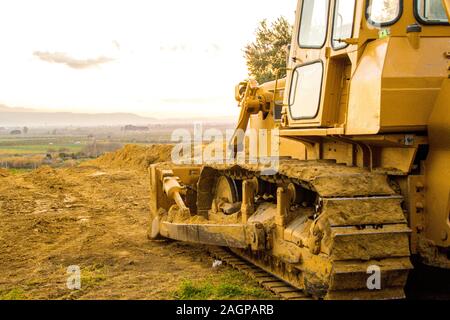 A yellow bulldozer is the workhorse of farmland. This old machine sits dormant awaiting it's next task(s). Stock Photo