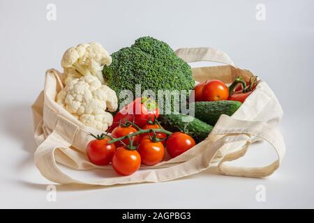 Zero waste concept. Vegetables in eco friendly reusable beige textile bag on white background. Plastic free. Healthy fresh vegetarian food. Stock Photo