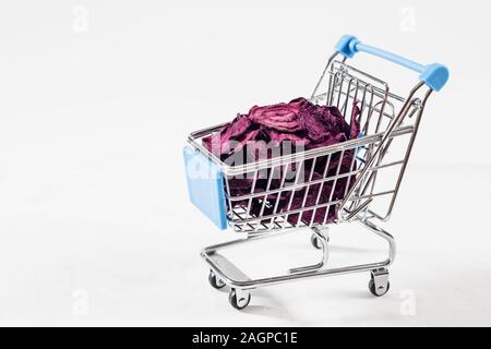 Dried beet chips in a toy grocery cart on a white background. Organic natural food. Concept vegan shopping. Copy space. Stock Photo