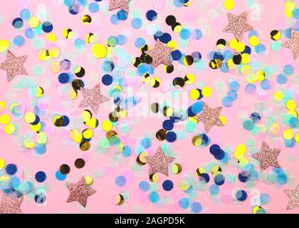 Multicolored confetti in the shape of a star and a dot on a pink background. Christmas and New Year concept. Stock Photo