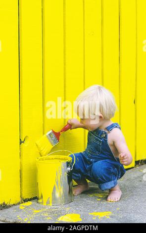 Two Year Old Boy Painting a Fence Yellow Stock Photo