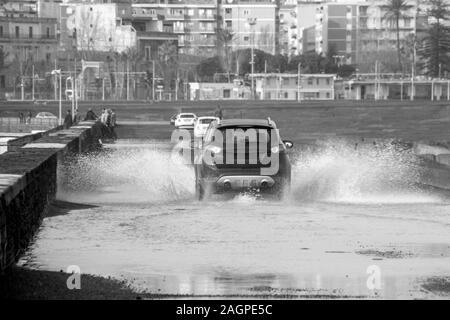 A car driving fast through a large puddle Stock Photo