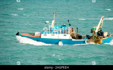 A small fishing boat heading out to sea to begin fishing. Stock Photo