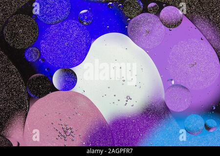 Colorful abstract background. Purple, blue circles and oil bubbles in the water closeup. Macro abstraction. Rainbow oil texture and pattern. Stock Photo