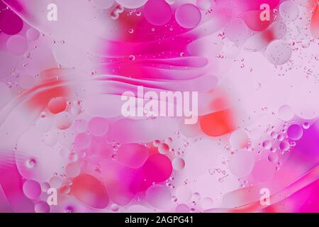 Colorful abstract background. Pink circles and oil bubbles in the water closeup. Macro abstraction. Rainbow oil texture and pattern. Stock Photo
