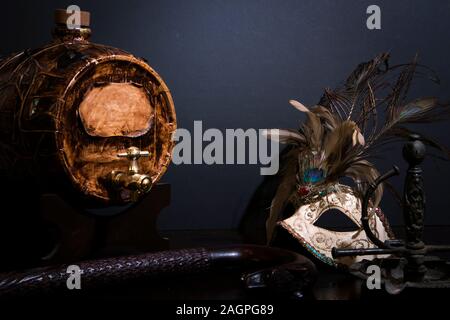 Stylish wooden keg, venetian mask and candle holder standing on the table Stock Photo