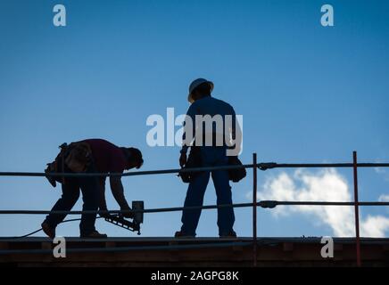 Construction Workers Silhouette on Roof of Building. Stock Photo