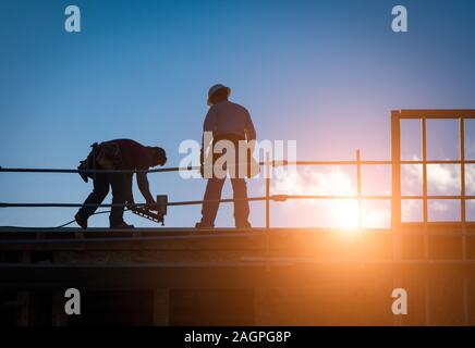 Construction Workers Silhouette on Roof of Building. Stock Photo