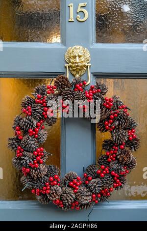Christmas holiday wreath with pine cones and red berries, on door, England Stock Photo