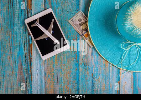 Concept of travel tourism devices tablet touch pad blue hat preparation for traveling and US dollar banknotes Stock Photo