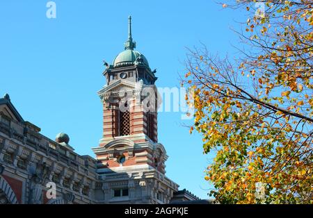 NEW YORK, NY - 04 NOV 2019: Closeup of a tower atop the National Museum of Immigration at Ellis Island with fall foliage. Stock Photo