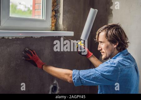 Man in a blue shirt does window installation Stock Photo