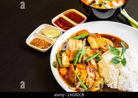 Thai-style Stir-fried Mixed Vegetables Tofu, with jasmine white rice, and a bowl of Tom Yum Soup in the background.Thai-style Stir-fried Mixed Vegetab Stock Photo