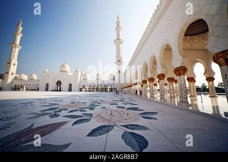 Dubai, United Arab Emirates - December 02, 2019:  Courtyard of  famous White Grand Sheikh Zayed Mosque with high; golden minarets with  blue sky backg Stock Photo