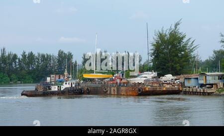 Miri, Malaysia - November 16, 2019: A boat and a floating platform with gravels near to the Miri Marina Terminal. Stock Photo