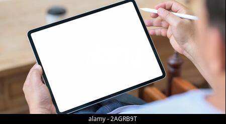 Close-up view of young man using blank screen tablet in comfortable room Stock Photo