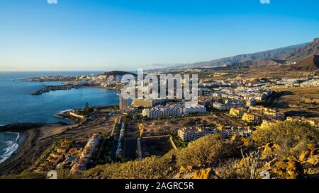 Spain, Tenerife, Aerial view above skyline, houses, skyscrapers and beach of los christianos tourist resort south of the island in warm sunset light Stock Photo