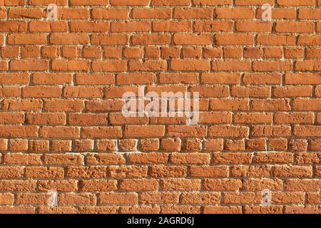 Shabby chic old rugged clay brick wall texture background with low angle sunlight showing scarred surface markings Stock Photo