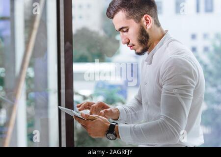Cropped closeup of young arab ethnency man using tablet pc indoor Stock Photo