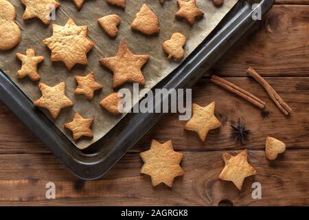 Baking gingerbread cookies on a baking sheet. Wood background. Stock Photo