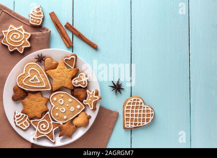 Ginger cookies decorated with icing on a plate on a blue wooden background. Top view, place for text. Stock Photo