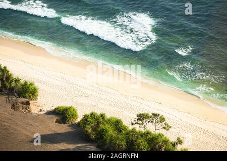 View from above, stunning aerial view of a beautiful wild beach bathed by a rough sea during sunset. Stock Photo