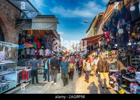 Historical Kemeralti Market in Izmir, Turkey. People walking through market and at sitting at traditional Turkish coffee shop in the historic bazaar Stock Photo