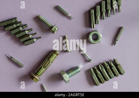 Bolts, nuts, screws and anchor bolt on a light pink background. Top view on metal fasteners and tools. Close-up. Stock Photo