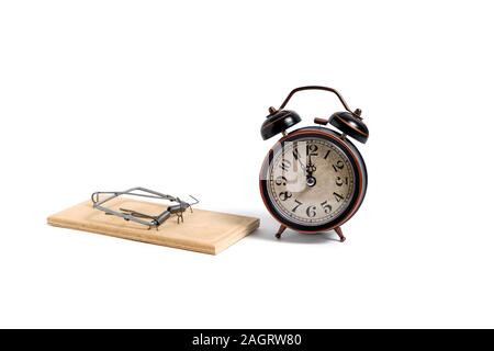 Old retro alarm clock next to wooden mousetrap on white background Stock Photo