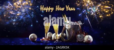 Happy New Year banner with champagne bottle and glasses, christmas decorations and fireworks against a dark blue background in panoramic format Stock Photo
