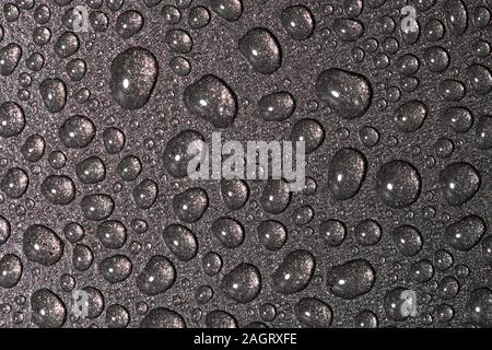A close up abstract macro photo of water droplets on a grey non stick frying pan material Stock Photo