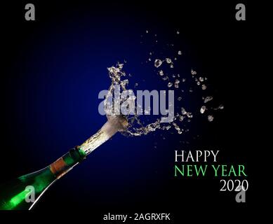 Happy New Year 2020 text and a champagne bottle exploding and shooting out the cork with splashes against a dark blue background, copy space Stock Photo