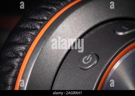 A close up macro photo of the power button on a pair of generic headphones with curved lines Stock Photo
