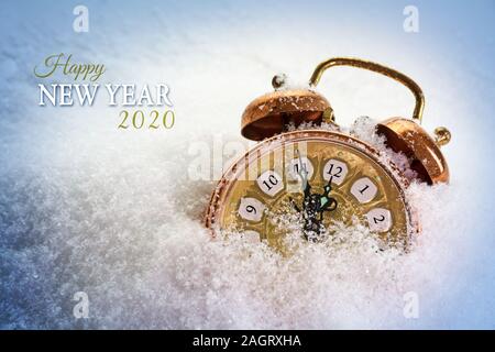 Happy New Year 2020 text and a vintage alarm clock in the snow shows five minutes before twelve, concept greeting card with copy space Stock Photo