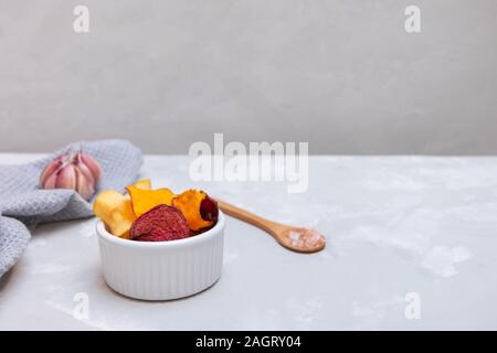 Mixed vegetable chips made from beetroot, carrot, sweet potato, parsnip seasoned with sea salt on concrete grey background, copy space Stock Photo