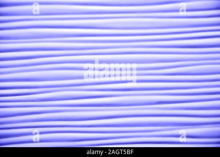 Close-up of artificial textured surface with simple wave pattern toned in shades of purple color. Plenty of smooth horizontal wavy lines. Empty abstra Stock Photo