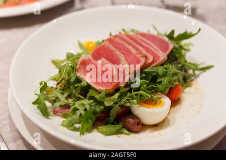 Meat carpaccio with arugula olives and soft-boiled egg. Serving in a restaurant Stock Photo