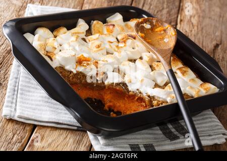 Sweet potato casserole with pecans topped with marshmallows close-up in a baking dish on the table. horizontal Stock Photo