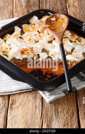 Festive sweet potato dessert with pecans and marshmallows close-up in a baking dish on the table. vertical Stock Photo