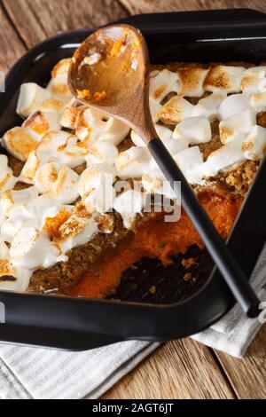 American sweet potato casserole with pecans and marshmallows close-up in a baking dish on the table. vertical Stock Photo