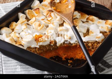 Traditional sweet potato dessert casserole with pecans and marshmallows close-up in a baking dish on the table. horizontal Stock Photo